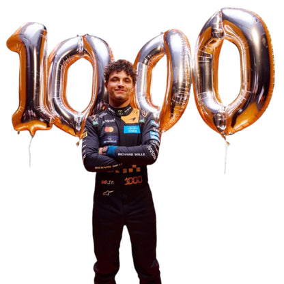 Lando Norris 2026 McLaren 1000th Monaco GP F1 race suit featuring a black, papaya orange and blue colourway with special edition McLaren detailing