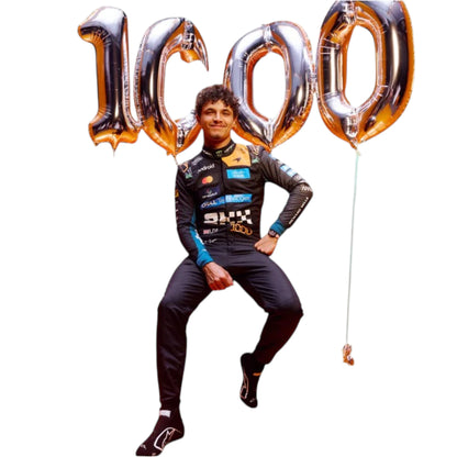 Lando Norris 2026 McLaren 1000th Monaco GP F1 race suit featuring a black, papaya orange and blue colourway with special edition McLaren detailing